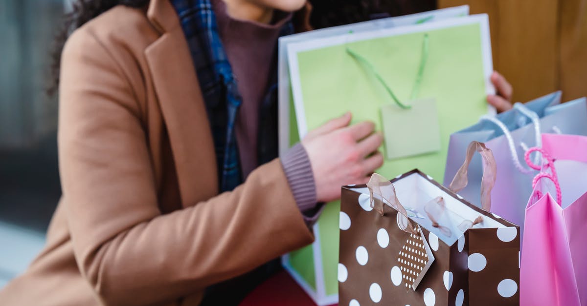 What is the difference between normal and special edition? - High angle of crop female in coat sitting at table with colorful gift bags placed on table