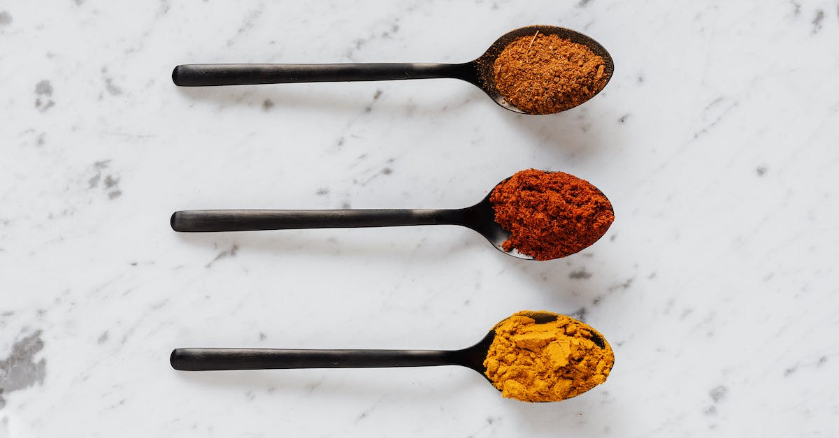 What is the difference between the yellow and brown exploding barrels? - Top view of dry curcuma with smoked paprika and mix of ground peppers on plastic spoons on marble table What is the difference between the yellow and brown exploding barrels? - Top view of dry curcuma with smoked paprika and mix of ground peppers on plastic spoons on marble table