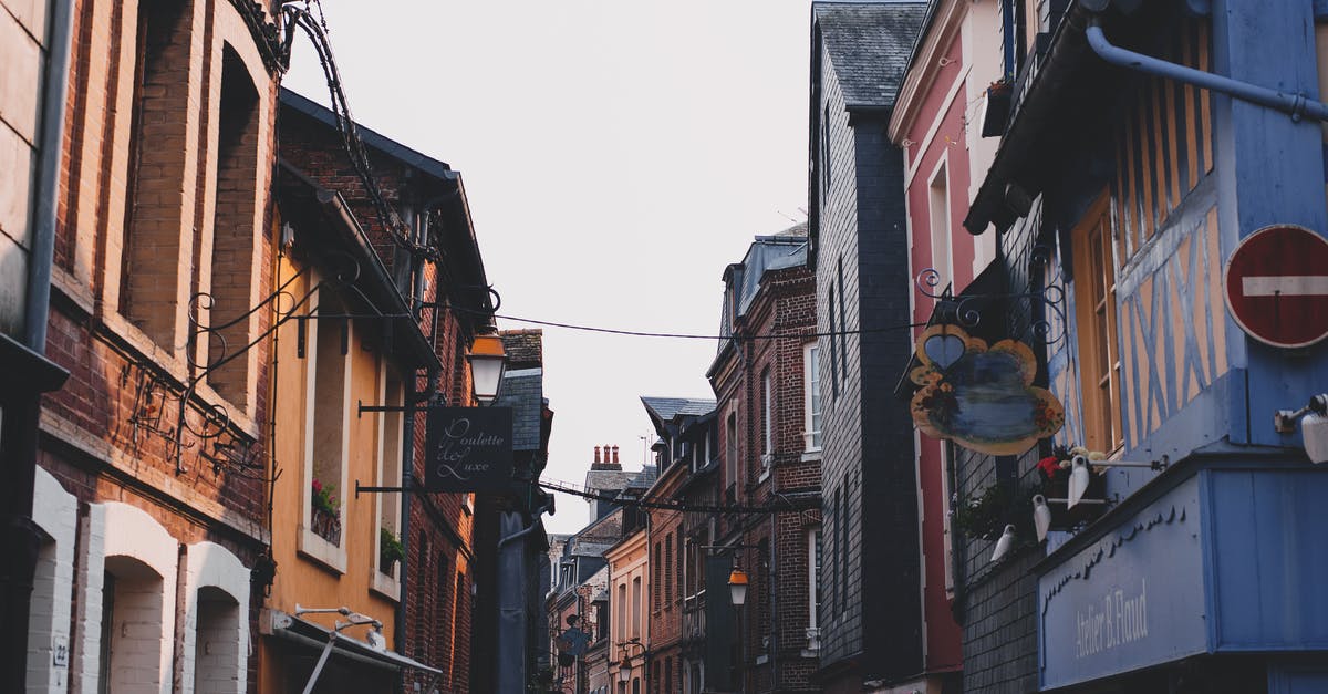 What is the differences between being home and away? - Narrow alley between typical buildings with colorful facade and brick walls located on street in town against cloudless sky in neighborhood