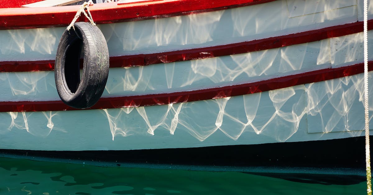 What is the effect of equipment position? - Red and white boat in calm rippling turquoise water of sea in daytime in summer