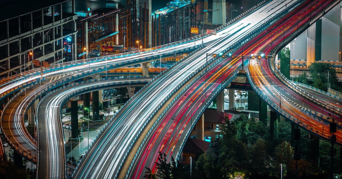 What is the fastest vehicle setup from the Catch-A-Ride? - From above long exposure traffic on modern highway elevated above ground level surrounded by urban constructions in evening