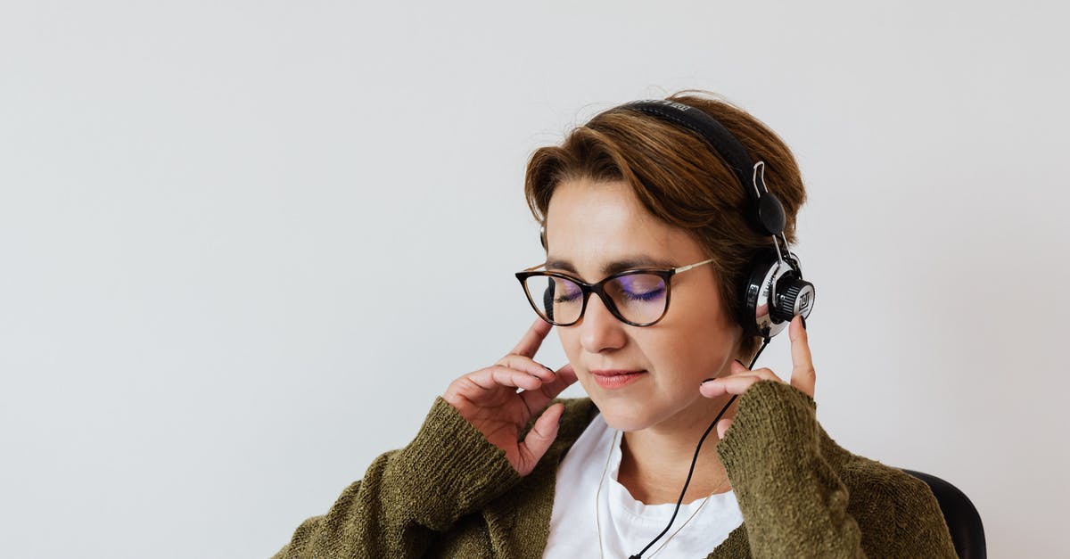 What is the favorite pokemons feature good for? - Content glad female wearing eyeglasses and headphones listening to good music and touching headset while sitting with eyes closed against white wall