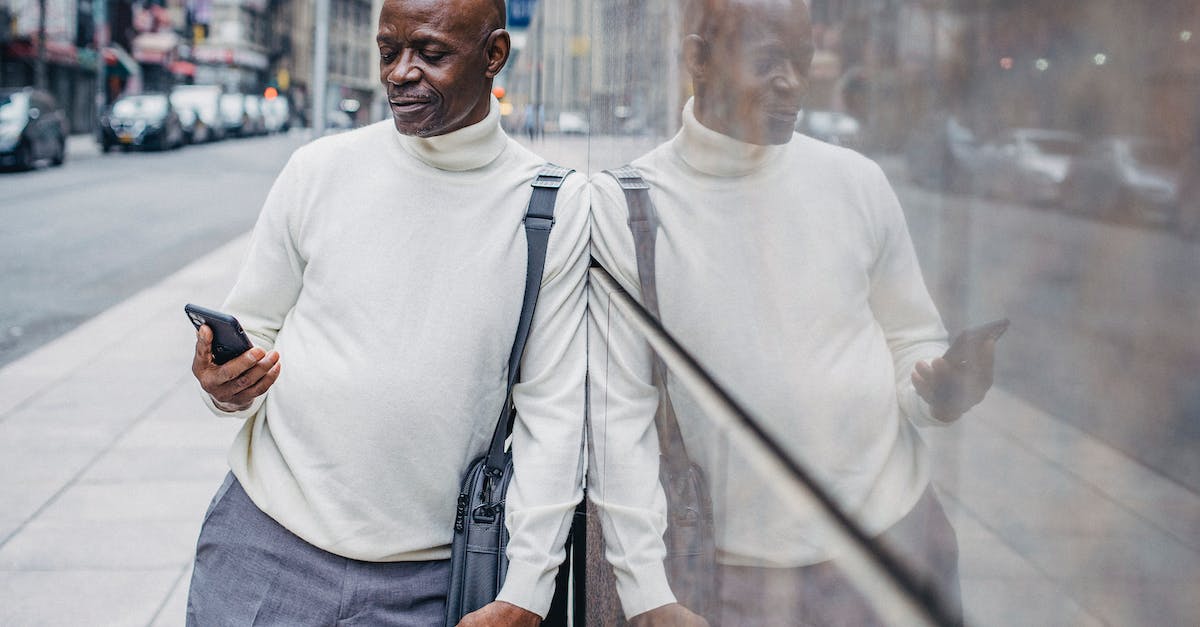 What is the Holo Caster message after you beat the Gym Leader in Lumiose City? - Serious African American man browsing smartphone while leaning on wall in downtown of city