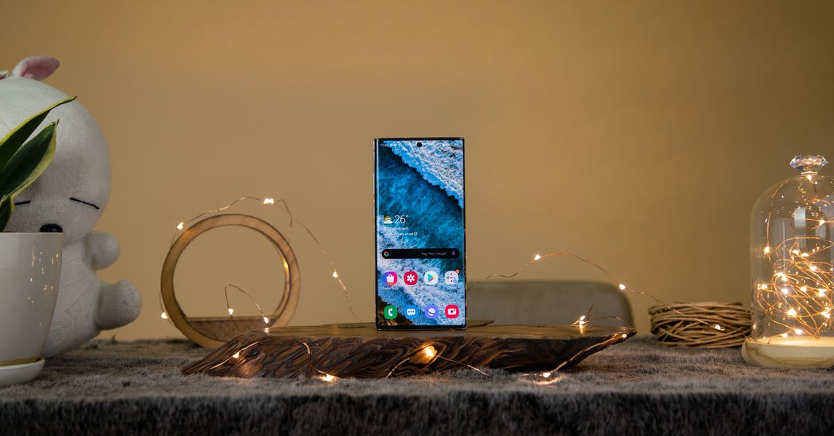 What is the magnifying glass icon in Fallout 4? - Contemporary cellphone with bright image on screen near glowing garland and decor on table on beige background