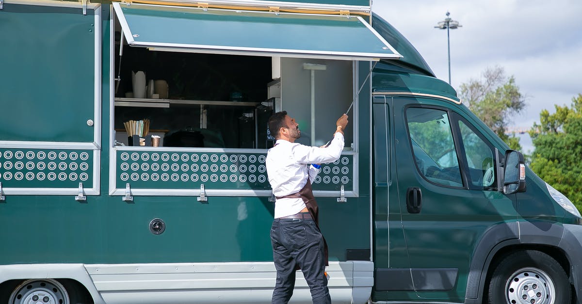 What is the maximum server View-Distance? - Side view young waiter in apron standing outside food truck and opening counter door in green lush park