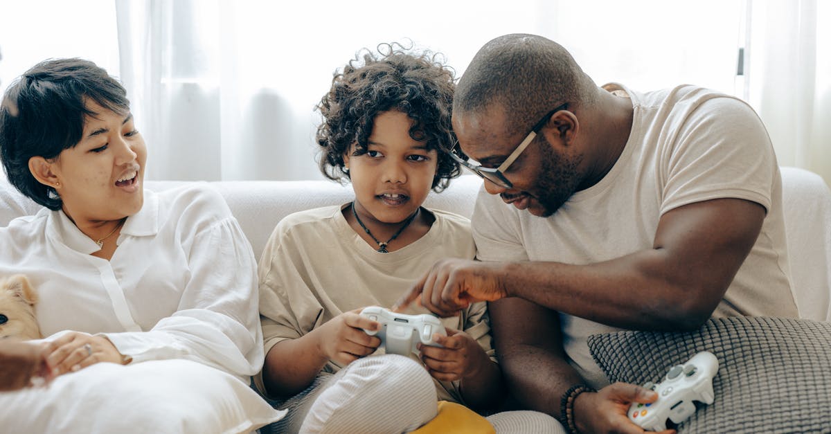 What is the point of having an alliance with your partner's family? - Concentrated black father pointing on joystick buttons explaining rules of playing to son while positive mother watching process What is the point of having an alliance with your partner's family? - Concentrated black father pointing on joystick buttons explaining rules of playing to son while positive mother watching process