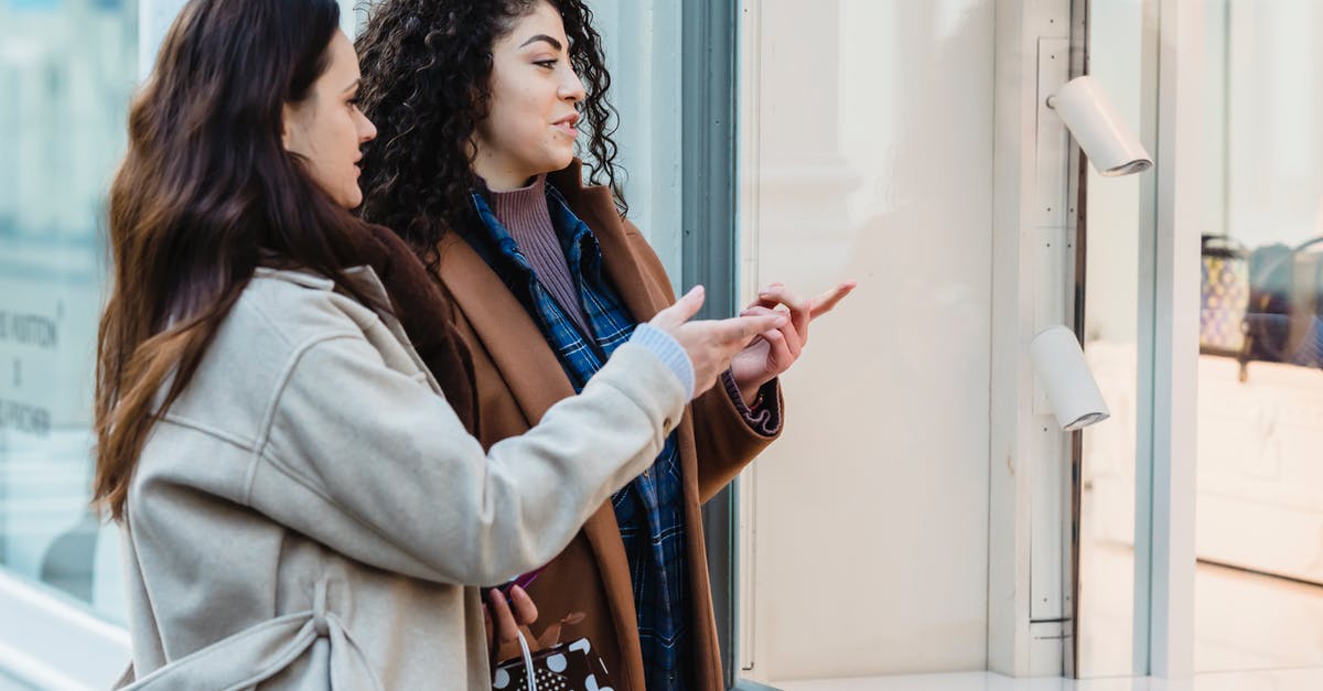 What is the point of investing in shops? - Side view of positive young multiracial female friends standing on city street and pointing on showcase of fashion boutique during shopping