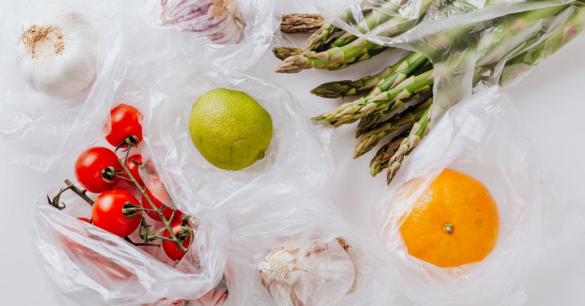 What is the point of Raw weapons? - From above of bunch of tomatoes with raw asparagus put into transparent plastic bags on white table near citrus fruits and garlic bulbs