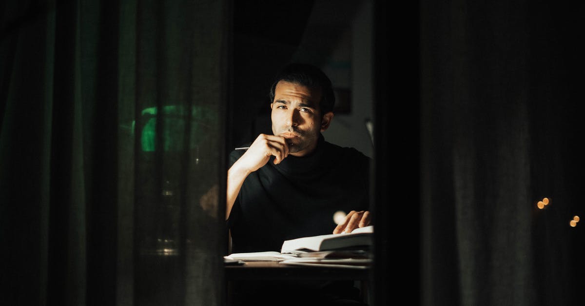 What is the story in Harry the Handsome Executive? - Serious young male wearing black turtleneck reading book and looking at camera while touching chin in contemplation and sitting at desk in dark home office