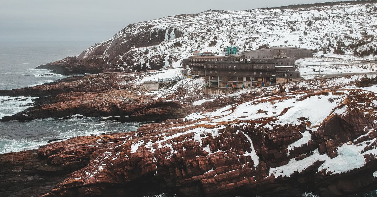 What is the weapon damage range formula? - Drone view of mountain range with forgotten buildings on cliffs covered with snow in overcast