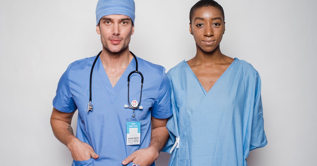What is this badge? - Positive male doctor in blue uniform with hands in pockets smiling and looking at camera while standing near nurse holding hands behind back in hospital What is this badge? - Positive male doctor in blue uniform with hands in pockets smiling and looking at camera while standing near nurse holding hands behind back in hospital