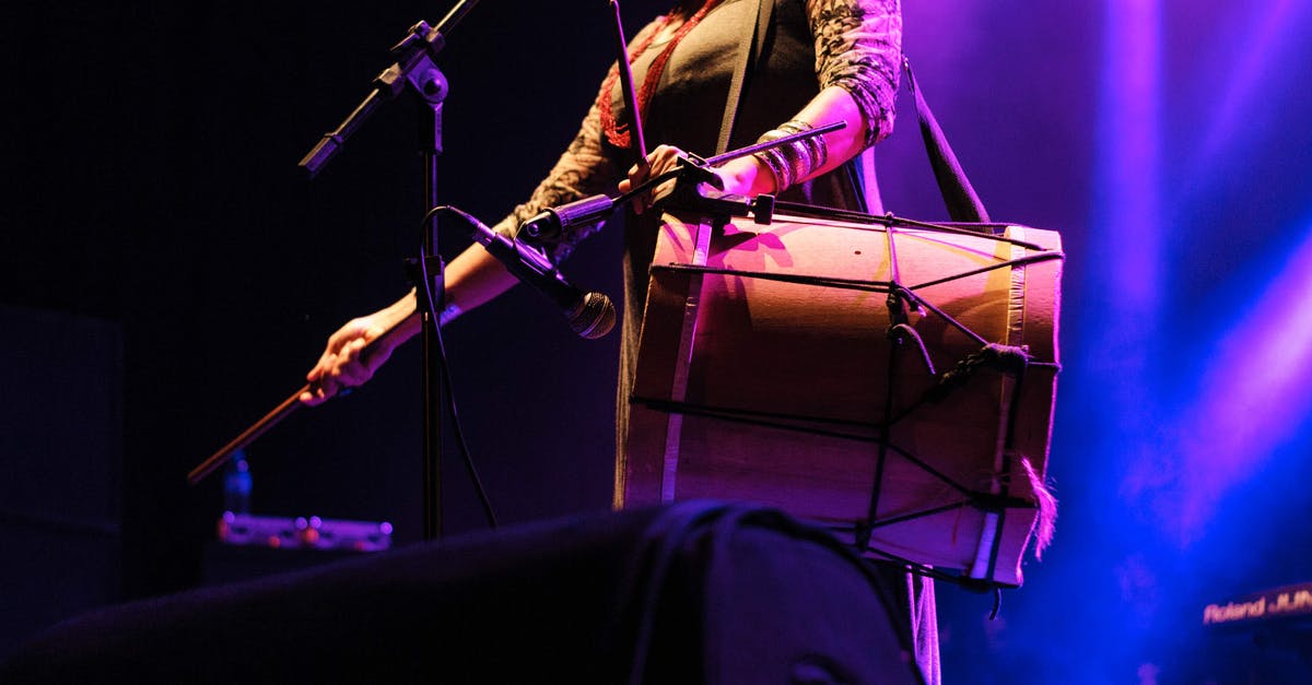 What is this glow over some players' weapons? - Unrecognizable skilled female musician with drumsticks playing drum while standing near microphone stand on stage during live concert on stage