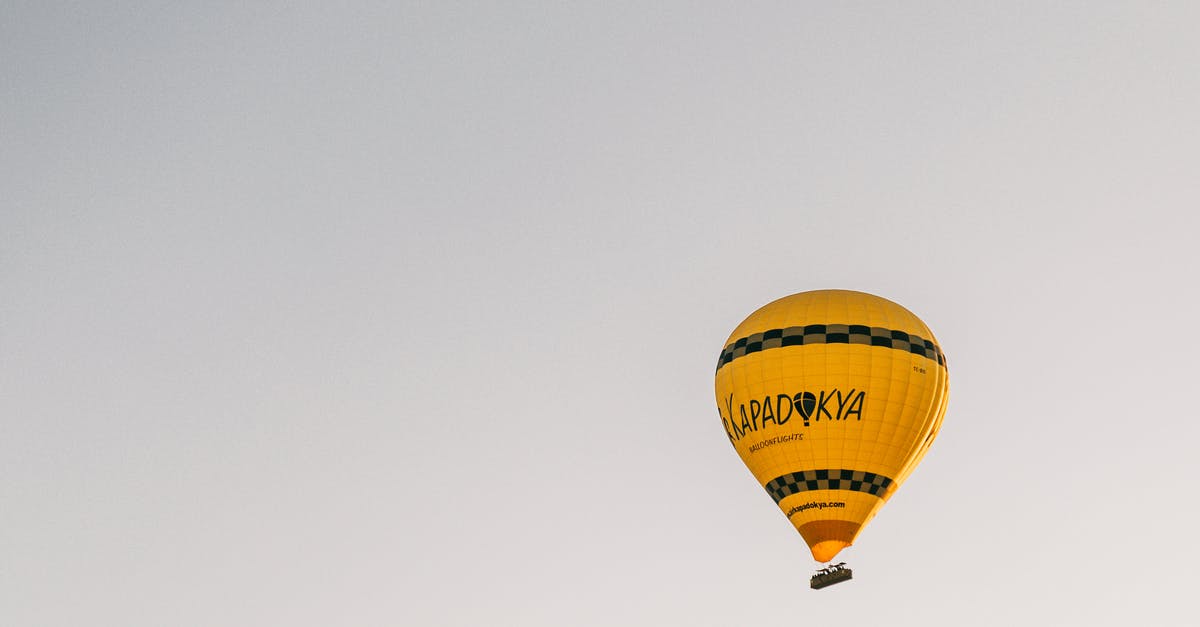 What is this yellow pillar of light from the sky? - From below of bright yellow hot air balloon flying in cloudless blue sky in Cappadocia in daytime