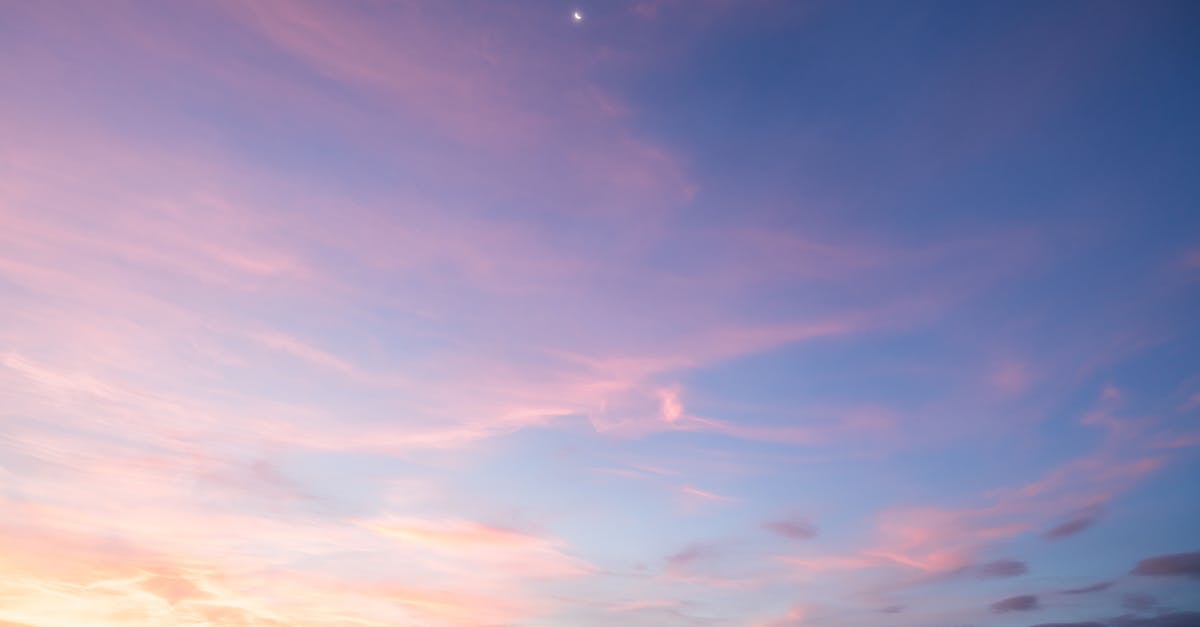 What is this yellow pillar of light from the sky? - From below of colorful sunset sky with tender light pink thin clouds at sundown