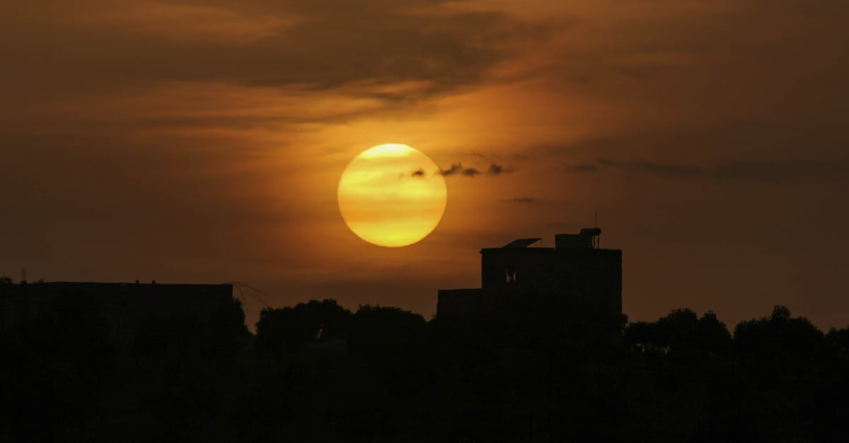 What is this yellow pillar of light from the sky? - Bright sun in sky over silhouettes of city houses