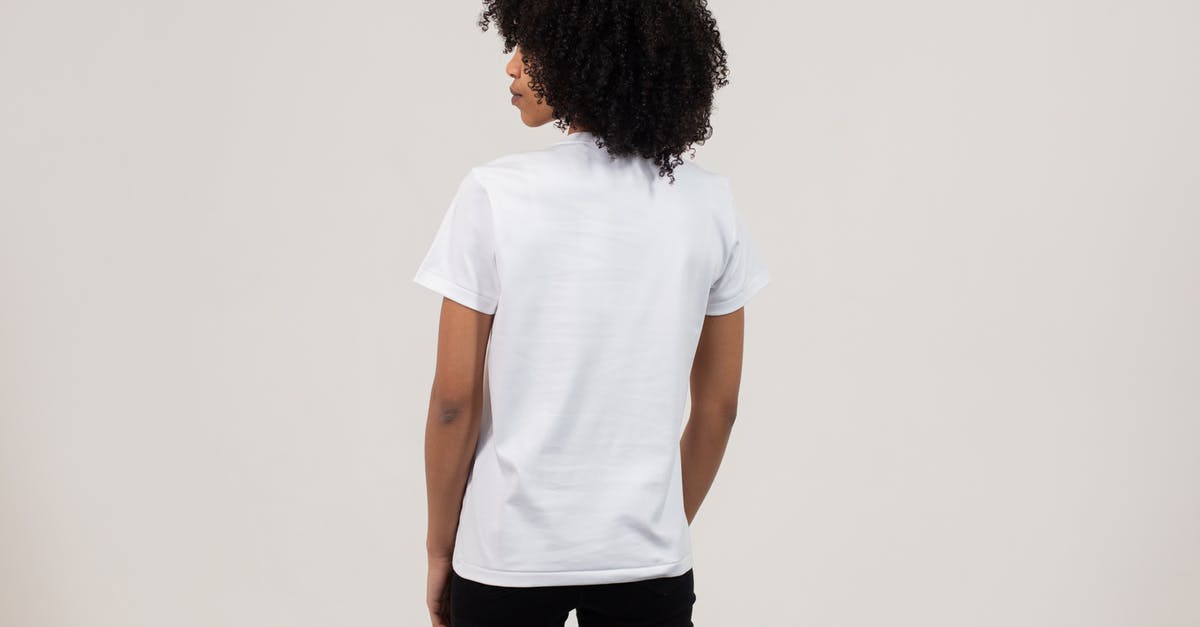 What items look like scrappable junk, but can't be scrapped? - Back view unemotional young African American female wearing casual white t shirt and black pants while standing against light wall
