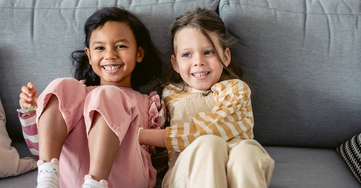 What kind of areas have folks been finding Gastly's? [duplicate] - Cheerful best multiracial friends in striped clothes interacting on couch in living room in house