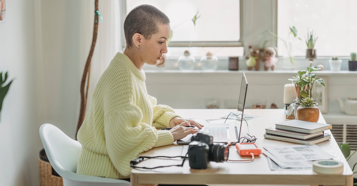 What kinds of external Hard drives are compatible with PS5? - Side view of concentrated female with short hair editing photos on netbook while sitting at table with photo camera in light room