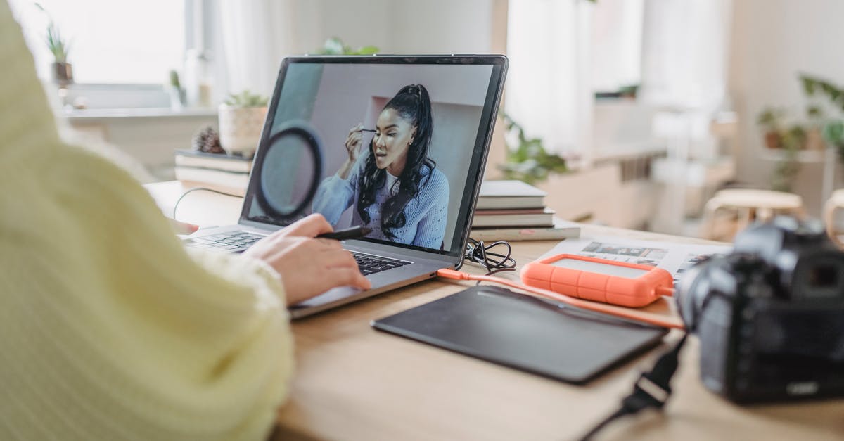 What kinds of external Hard drives are compatible with PS5? - Crop unrecognizable female photographer editing photo while sitting at table with photo camera and graphic tablet during work in spacious room with flowerpots