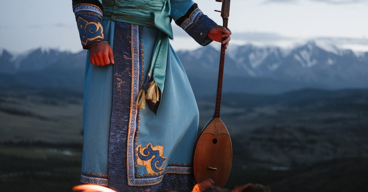 What Melodies can i play to my Mountain? - Crop person standing near bonfire with Mongolian folk instrument in valley