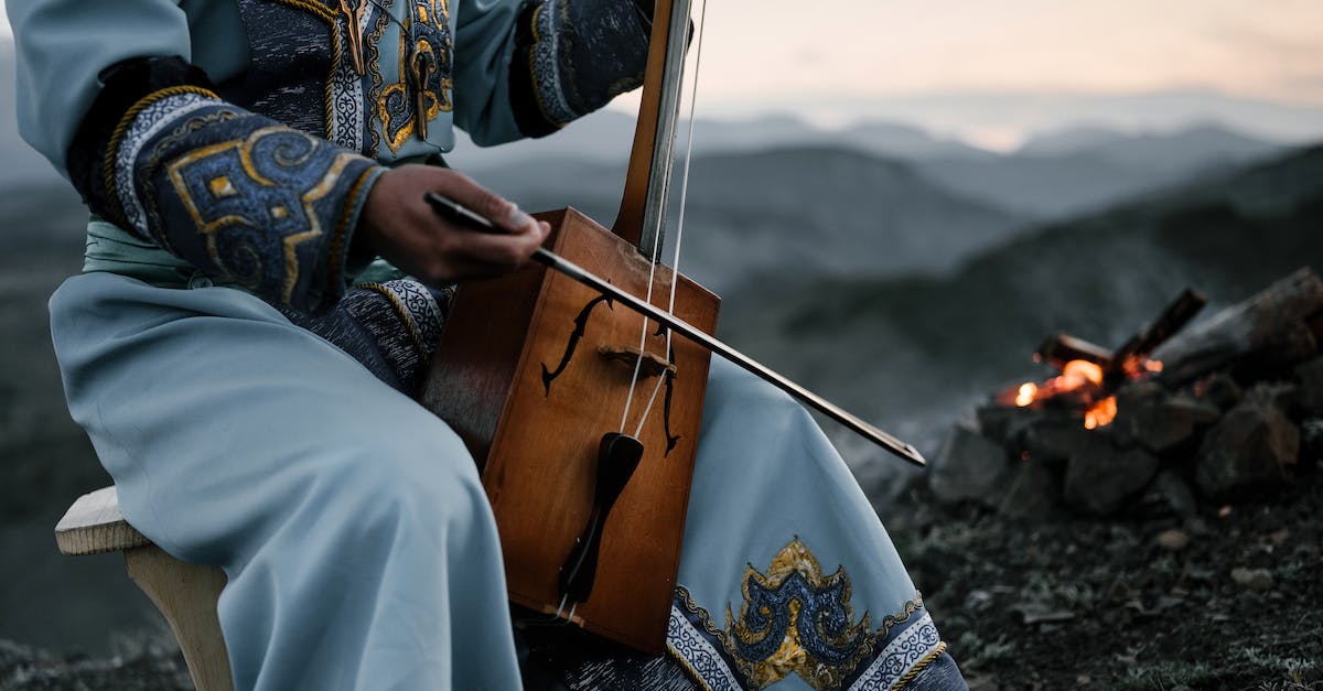 What Melodies can i play to my Mountain? - Crop person playing traditional Mongolian stringed instrument in countryside