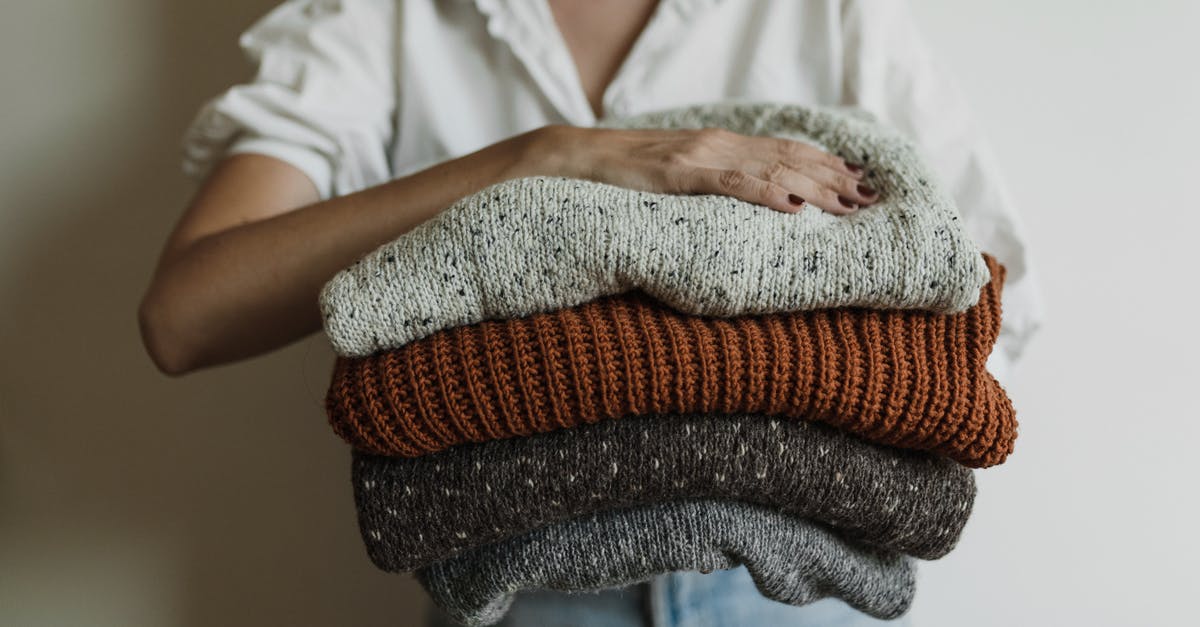 What pieces of warm clothing can be obtained on Zeah? - Woman Holding Pile of Knitted Sweaters What pieces of warm clothing can be obtained on Zeah? - Woman Holding Pile of Knitted Sweaters