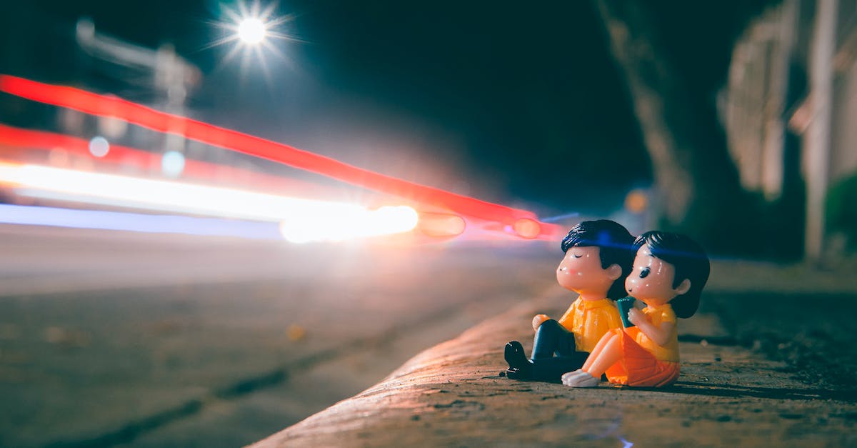 What route across levels 22-25 avoids all spikes? - Ground level of cute couple figurines on roadside near highway with long exposure light trails in evening time on blurred background