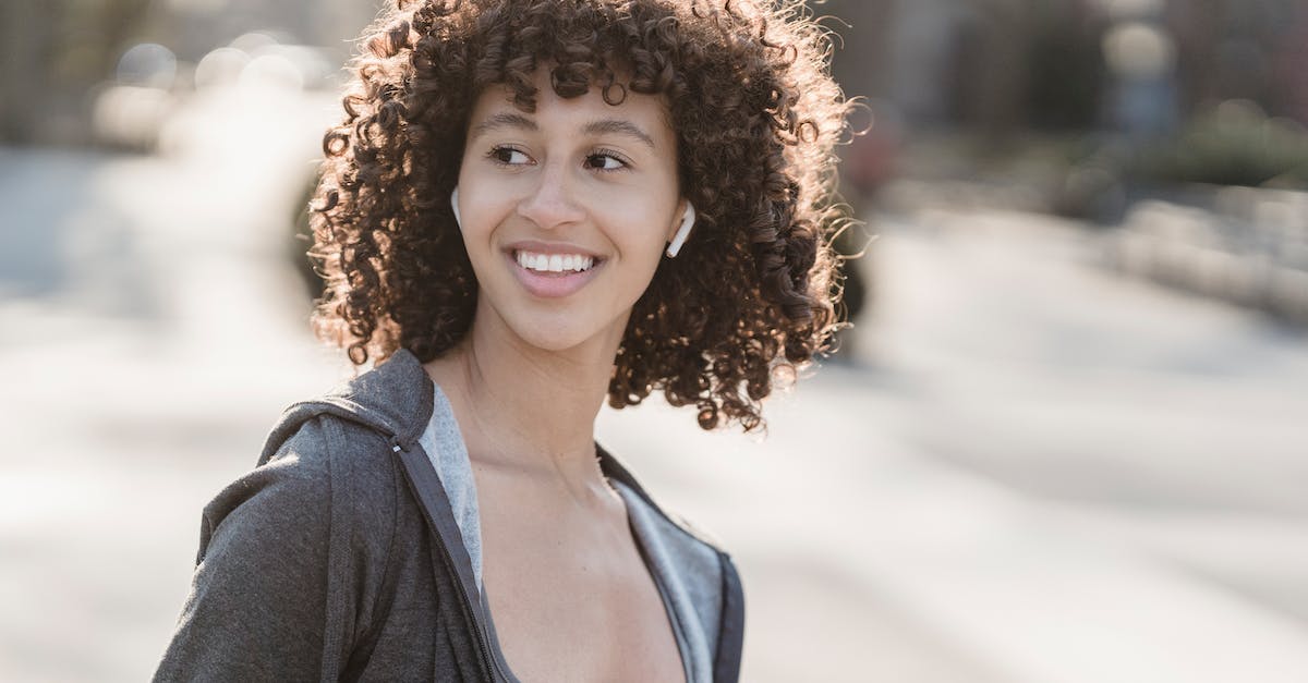 What song is playing in Cassie's earbuds during her intro? - Smiling ethnic sportswoman in earbuds on street