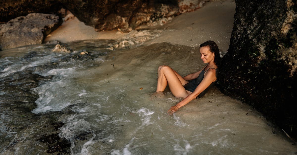 What stat should I increase to not get knocked down from body checks so easily in "Be a Pro"? - Positive woman in swimsuit leaning on mountain slope in water