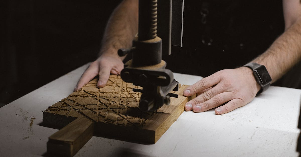 What stickers have special "scratched" patterns? - Unrecognizable male carpenter using special metal instrument to carve wooden board while working at workbench on black background in dark workshop