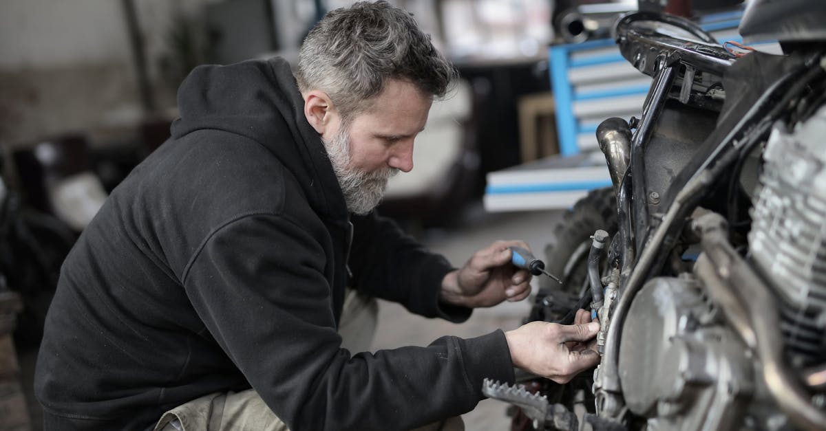 What types of equipment work when driving a spidertron? - Bearded man fixing motorcycle in workshop What types of equipment work when driving a spidertron? - Bearded man fixing motorcycle in workshop
