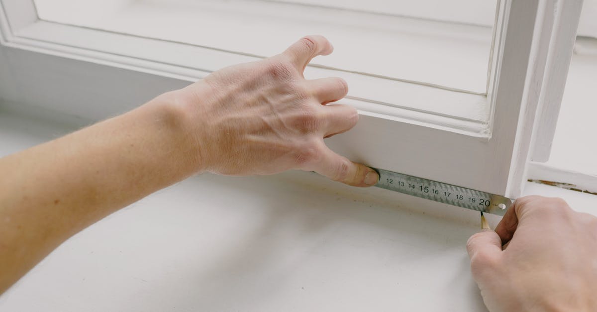 What unlocks new training from the masters? - From above of crop anonymous workman measuring wooden window frame using metal ruler and pencil in house