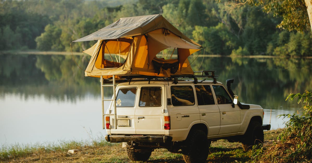 Whats happening to my off shore money? - Off road car with tent on roof parked on lake shore in forest Whats happening to my off shore money? - Off road car with tent on roof parked on lake shore in forest