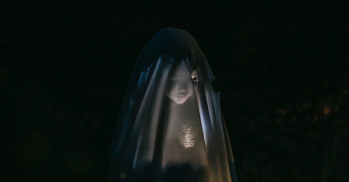 Whats the point of increasing flashlight accuracy? - Mysterious little girl standing in darkness covered with white blanket as ghost and shining flashlight on face