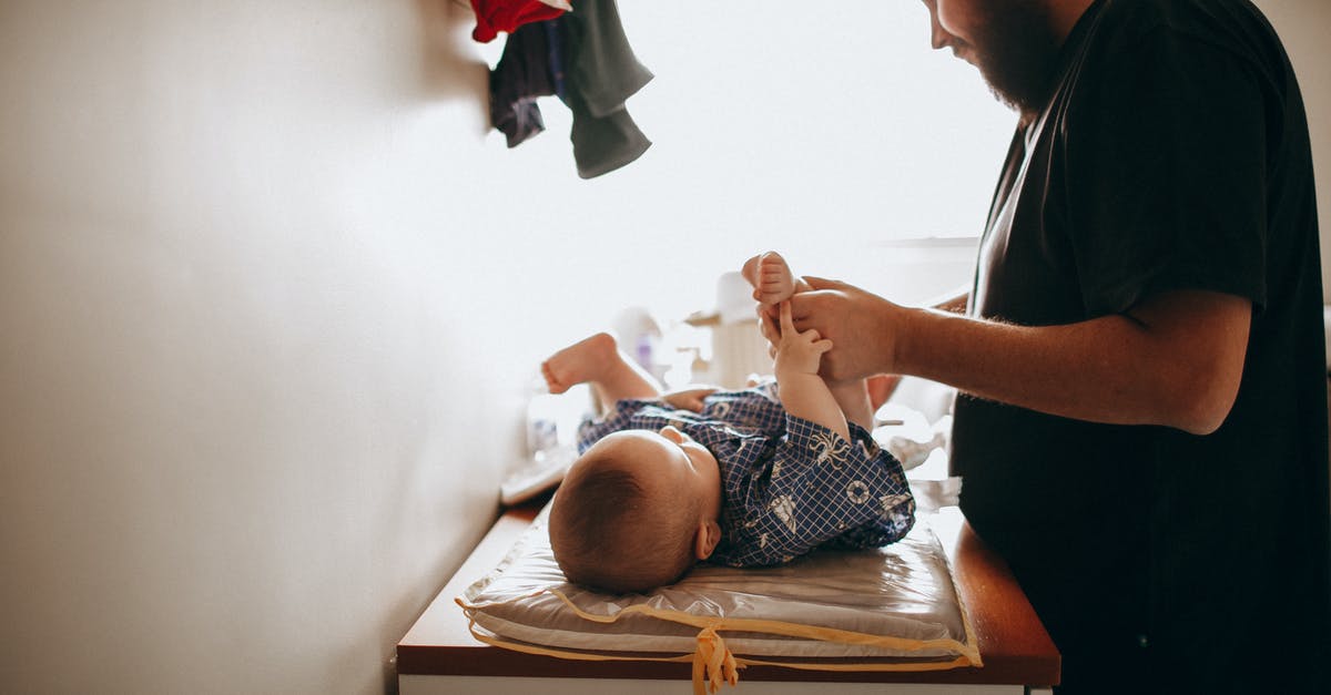 When a baby grows up into a toddler can I change its outfit? - Young father changing diaper of newborn baby When a baby grows up into a toddler can I change its outfit? - Young father changing diaper of newborn baby