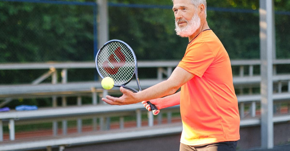 When does the game determine which fossils are which? - Side view of cheerful senior sportsman standing with ball and racket and preparing to serve ball on court in daytime