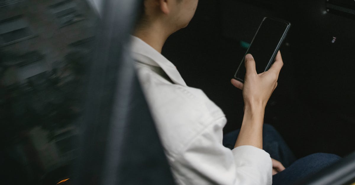 When stealing from cars, should I check the visor? - High angle of taxi passenger using smartphone while sitting on backseat
