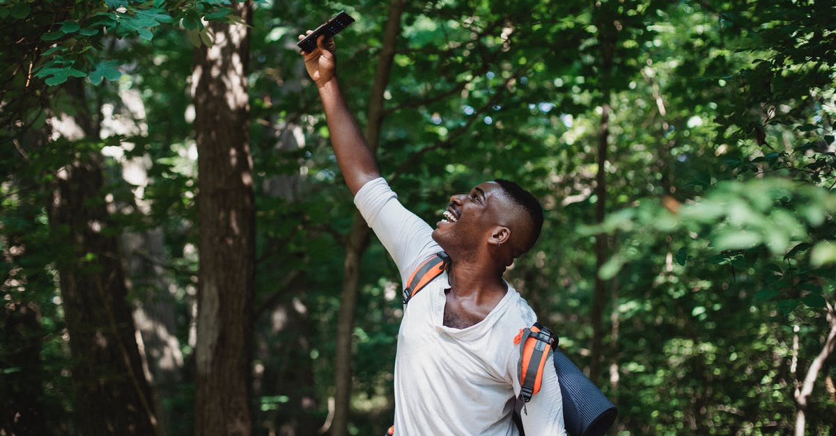 Where are Stellaris save games located? - Happy African American male with backpack and mobile phone finding connection during hiking