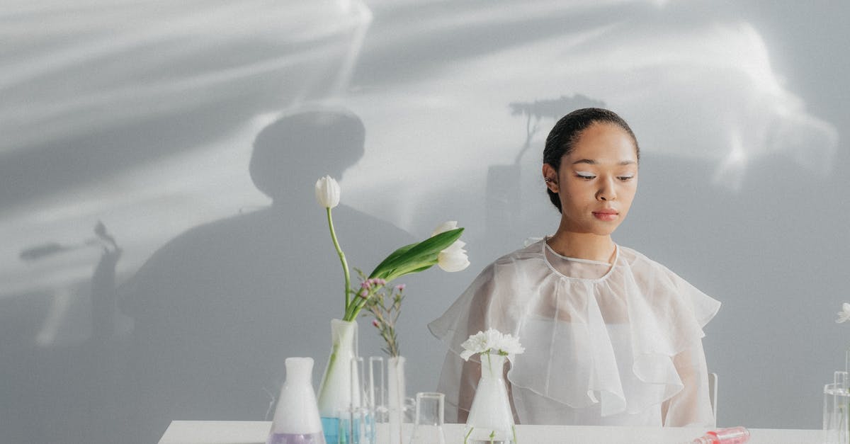 Where are the Aperture Science Logos? - A Woman in White Top Sitting at the Table with Flowers in Flasks
