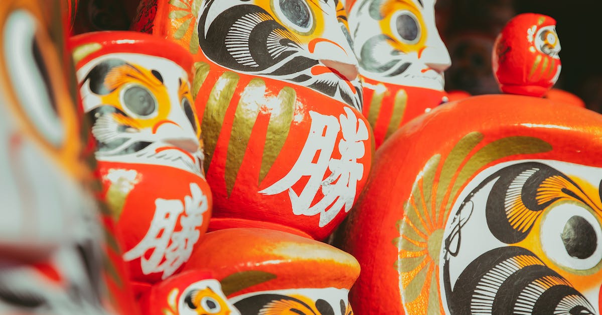 Where are the Origin settings on a Mac? - Collection of traditional Japanese red painted daruma dolls depicting bearded man stacked together on local market on street in city