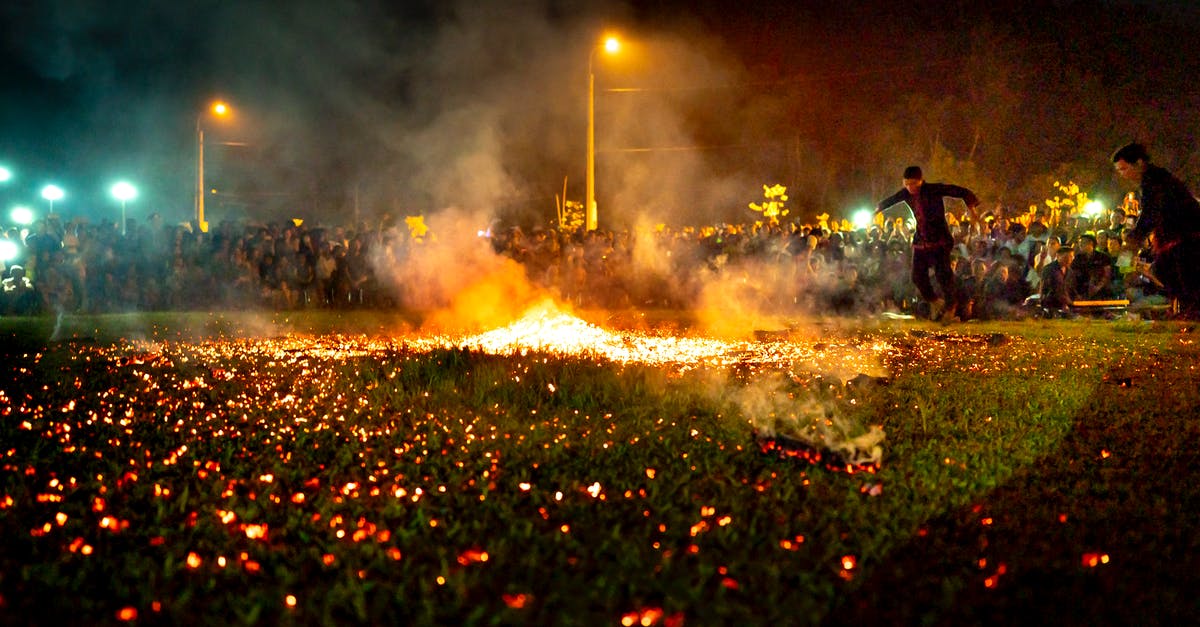 Where can fire spread to? [duplicate] - Ethnic male fire performers dancing on lawn with flame and smoke against anonymous spectators during show on lawn