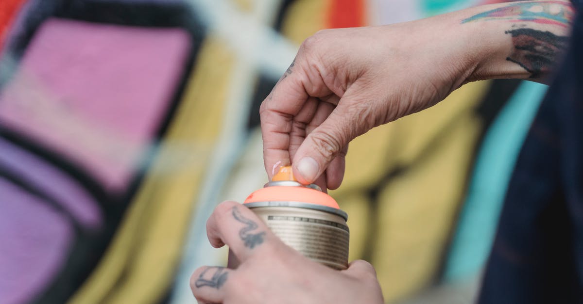 Where can I find the parts for a Shiskebab? - Soft focus of crop unrecognizable painter with tattoos opening spray paint can while standing near colorful wall with creative graffiti