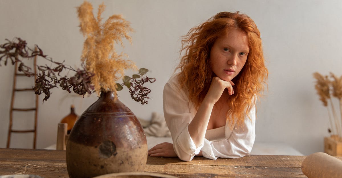 Where do players inside vents appear on the admin table? - Dreamy female with red hair looking at camera while leaning on hand at table with dry flowers in vintage vase
