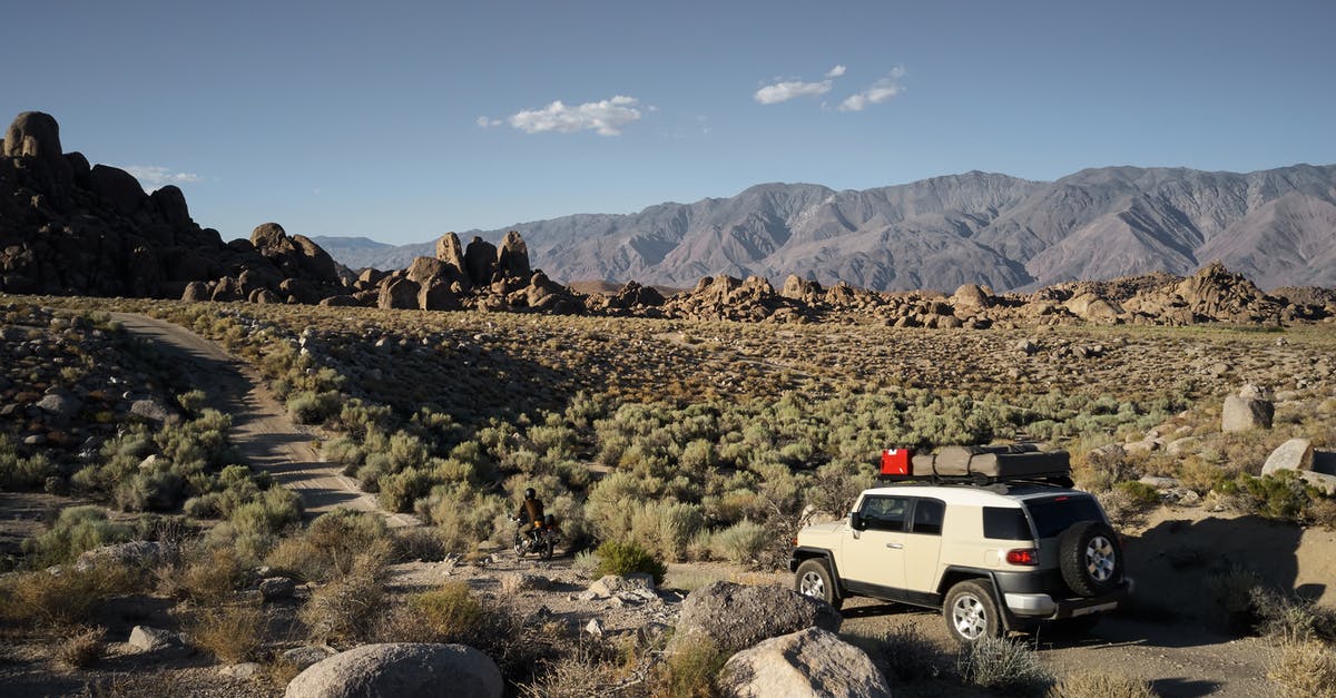 Where is "Northwest" in The Dusty Path? - Picturesque view of SUV and motorbike driving on dusty narrow road in mountainous semidesert terrain with dry vegetation in daytime against cloudless sky