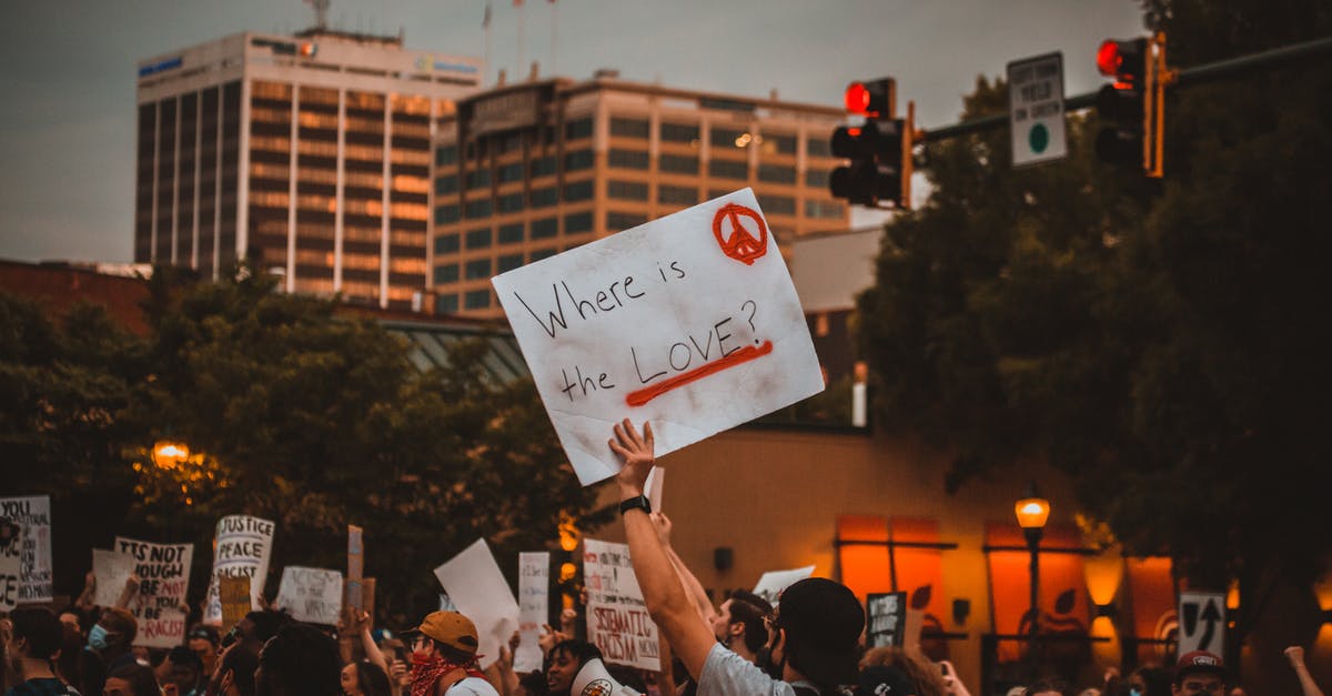 Where is the Benefactor? - Multiracial people with banners protesting on street in evening Where is the Benefactor? - Multiracial people with banners protesting on street in evening
