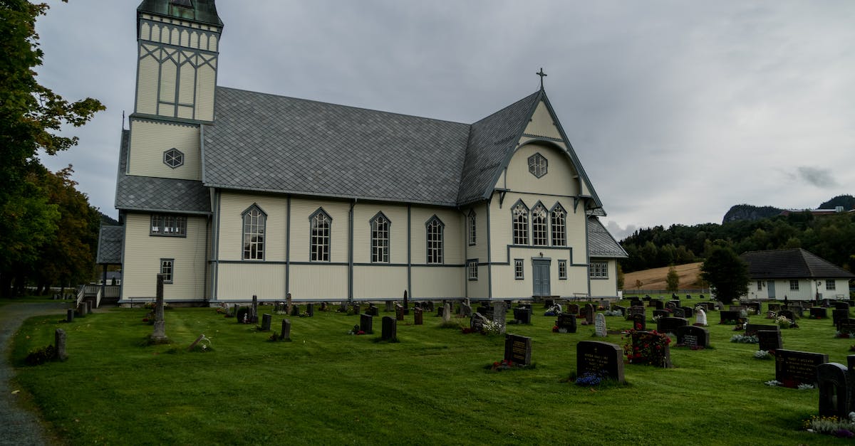 Where is the graveyard in Sims Medieval? - Exterior of old catholic chapel located near stone graveyard under gray sky in countryside in daytime