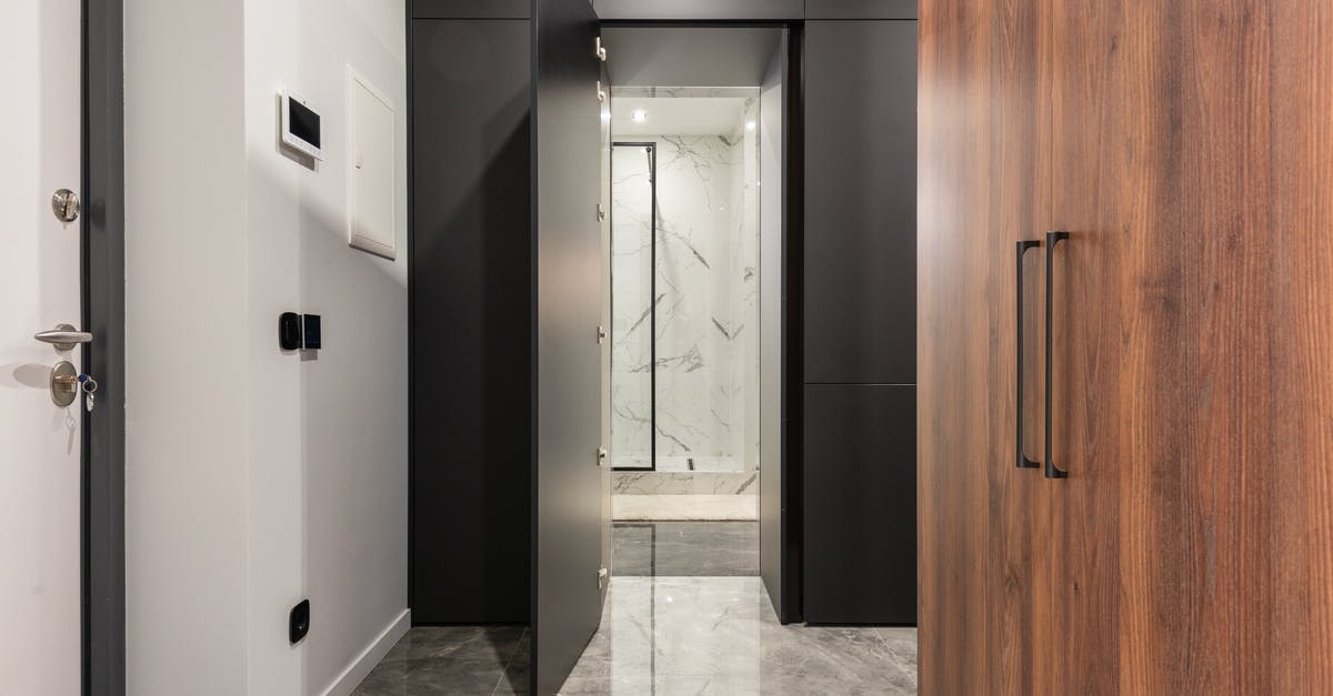 Where is the key to the guarded door? - Corridor with tiled marble floor and closet against doors in contemporary house with shiny lights