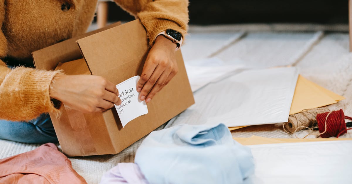 Where should I deliver the preparation data? - Crop unrecognizable woman sticking shipping label on parcel Where should I deliver the preparation data? - Crop unrecognizable woman sticking shipping label on parcel
