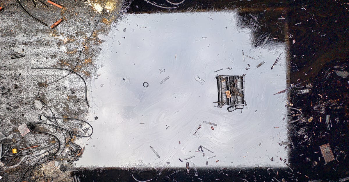 Where to find oil to extract with pump jack - Top view of black reflecting dirty river contaminated with oil products and litter Where to find oil to extract with pump jack - Top view of black reflecting dirty river contaminated with oil products and litter