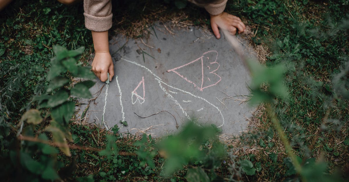 Which activity yields the most experience? - High angle of unrecognizable child drawing with chalks on small piece of concrete block in grassy yard Which activity yields the most experience? - High angle of unrecognizable child drawing with chalks on small piece of concrete block in grassy yard